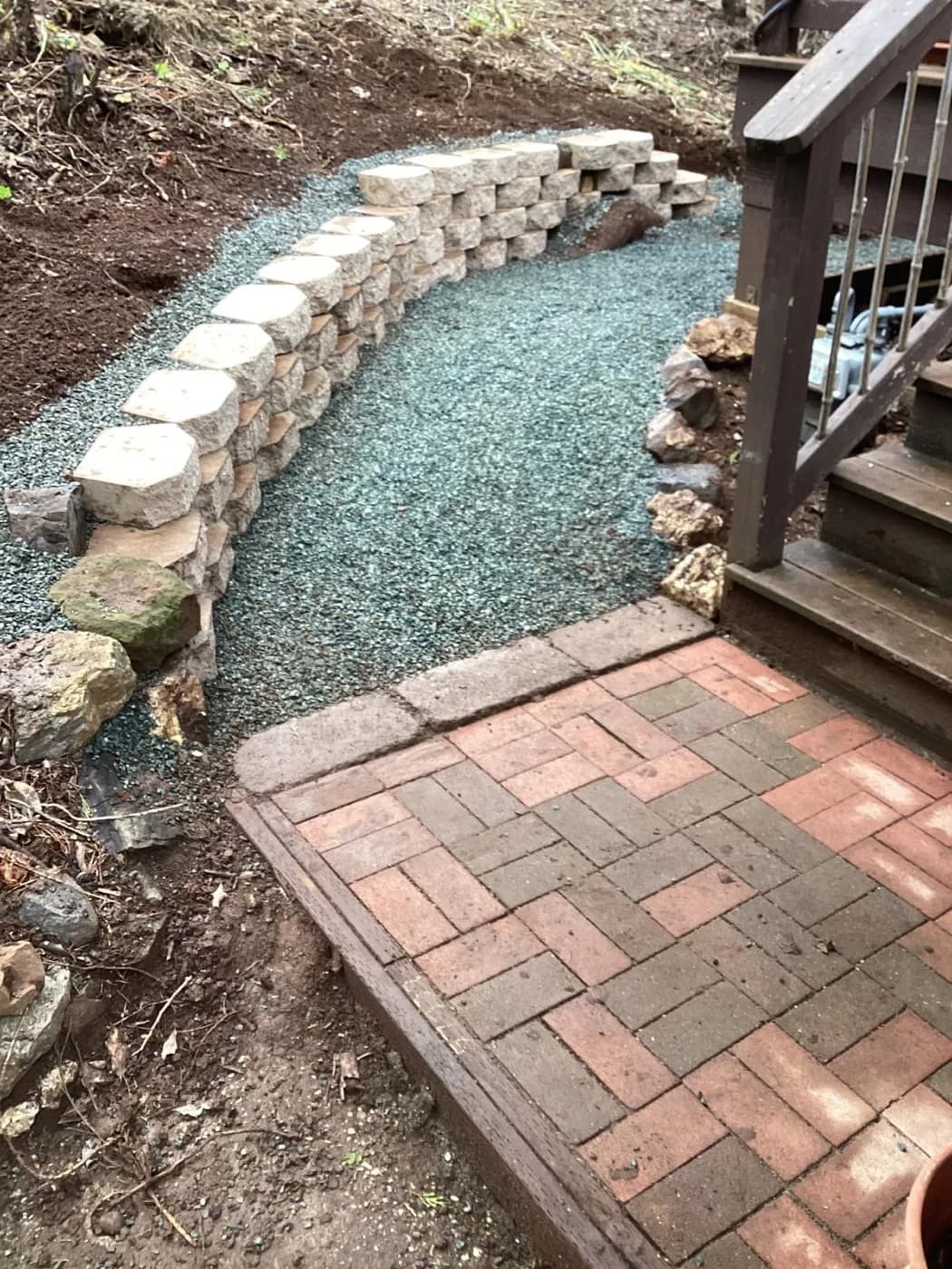 Stone retaining wall we built meeting a brick patio landing