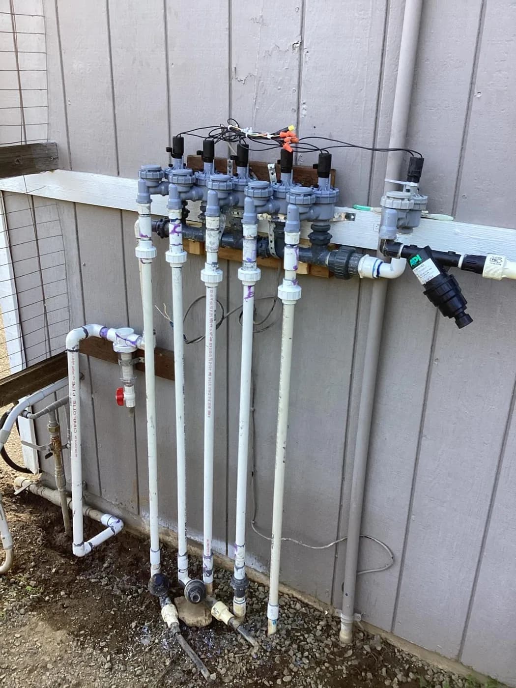 Irrigation valve manifold plumbed and mounted against an exterior wall